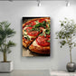 a large pizza with tomato and basil toppings, displayed on a wall in a room with a potted plant to the left and a plant to the right.