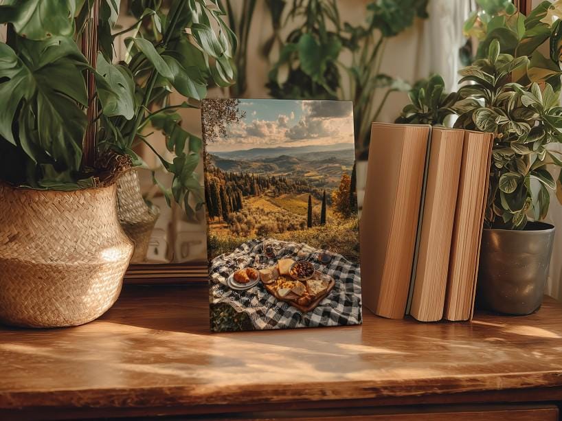 a wooden table with a framed photograph of a picnic scene, surrounded by potted plants and books.