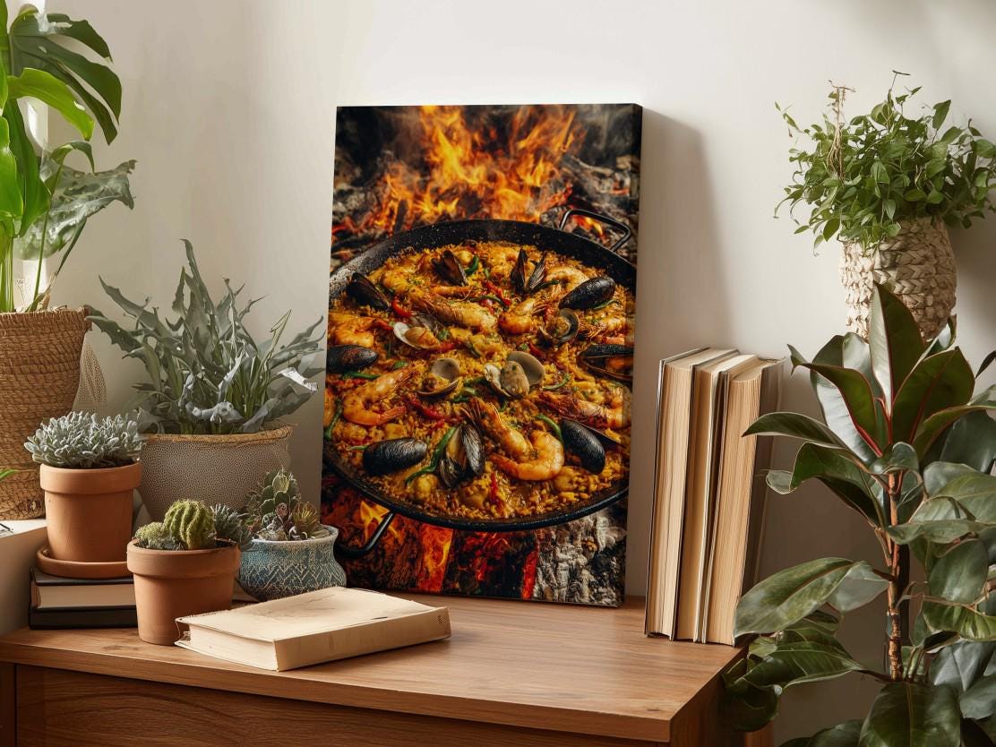a wooden table with a framed photograph of a paella dish, surrounded by potted plants and books.