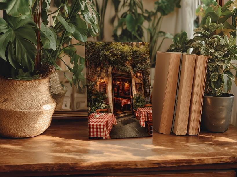 a wooden table with a framed photograph of a restaurant entrance, surrounded by potted plants and books.