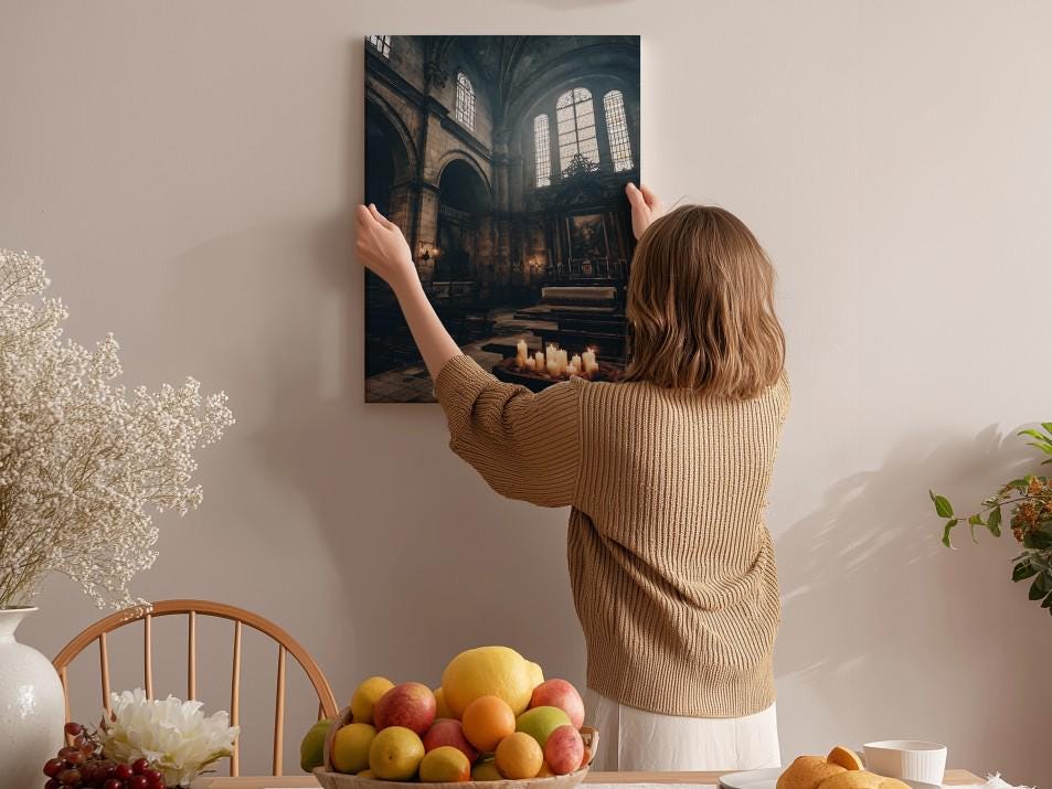A woman hangs a framed photograph of a church interior on a wall in a room with a dining table, chairs, and various decorative items.