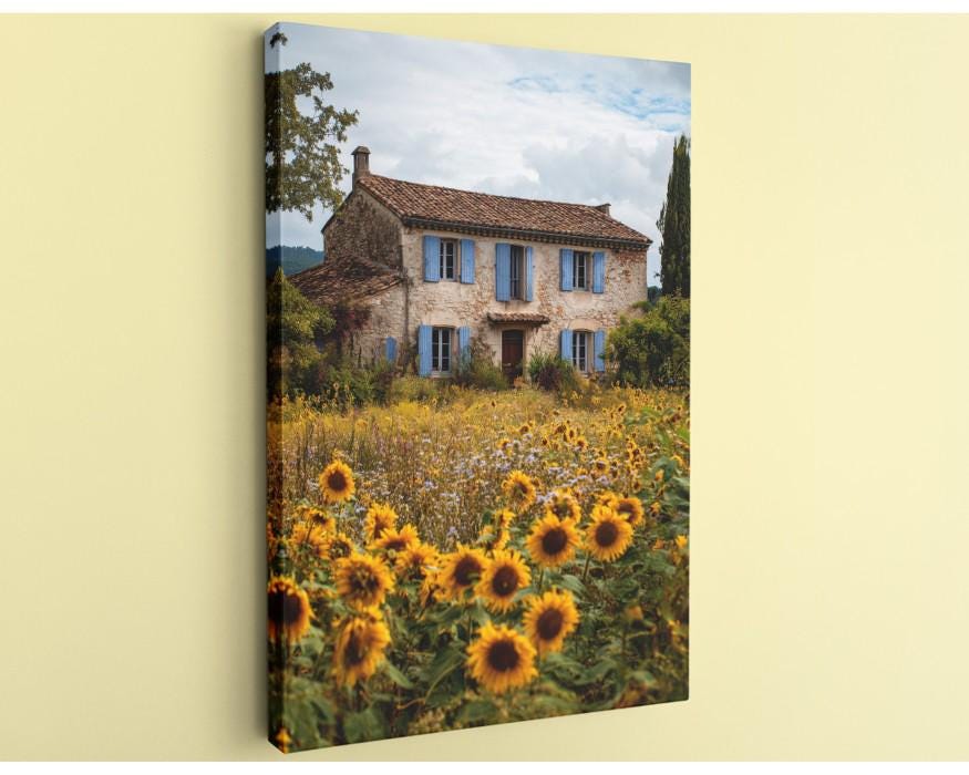 A picturesque scene of a two-story stone house surrounded by a vibrant field of sunflowers, set against a backdrop of a blue sky with clouds.