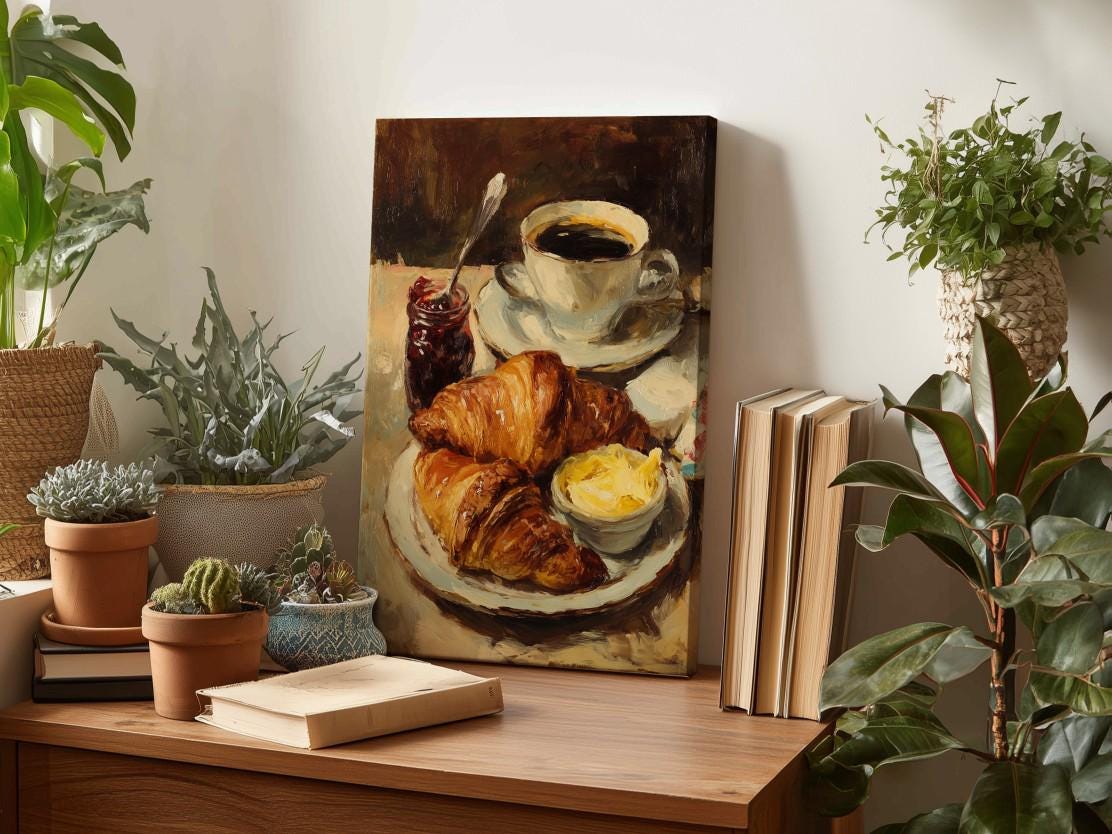 a painting of a croissant and butter on a plate, surrounded by potted plants and books on a wooden surface.