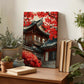 a wooden desk with a framed picture of a traditional Korean temple, surrounded by various potted plants and books.