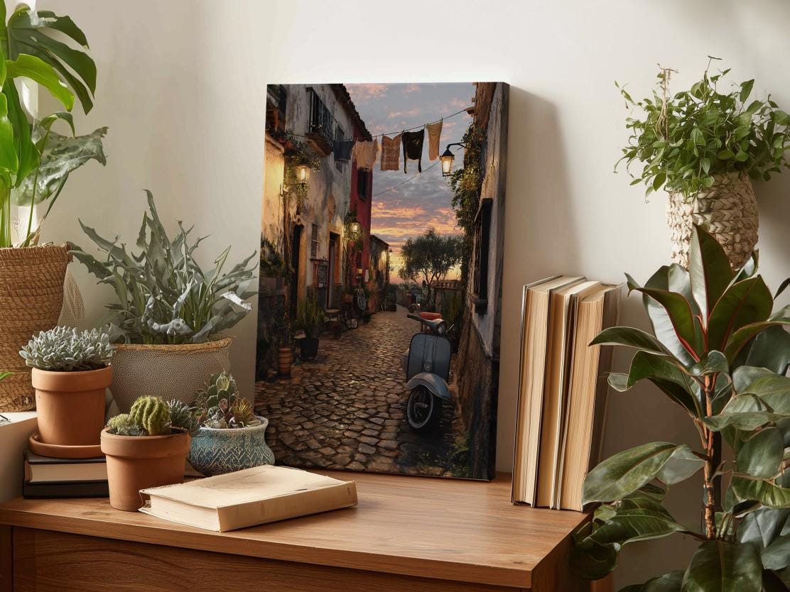 a cozy indoor setting with a wooden table displaying various potted plants, a book, and a framed picture of a cobblestone street at sunset.