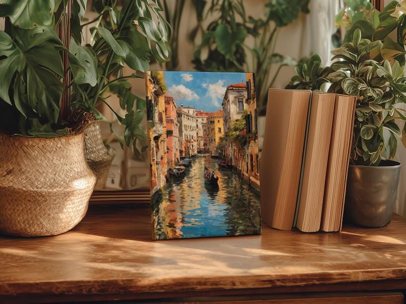 a painting of a canal scene with a gondola, surrounded by lush green plants and placed on a wooden surface.