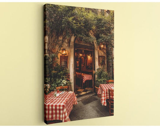 a cozy outdoor dining area with red and white checkered tablecloths, surrounded by lush greenery and a rustic stone wall.