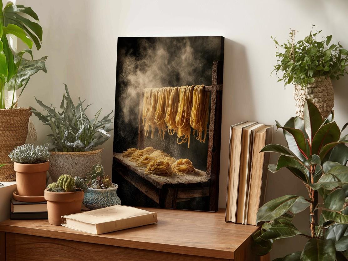 a wooden table with various objects on it, including a framed photograph of noodles drying on a rack, a stack of books, and several potted plants.