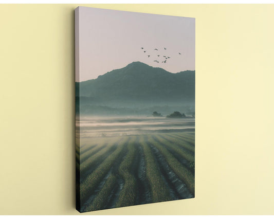 a serene landscape with a field of crops stretching out towards a mountain range in the distance, with a flock of birds flying overhead.