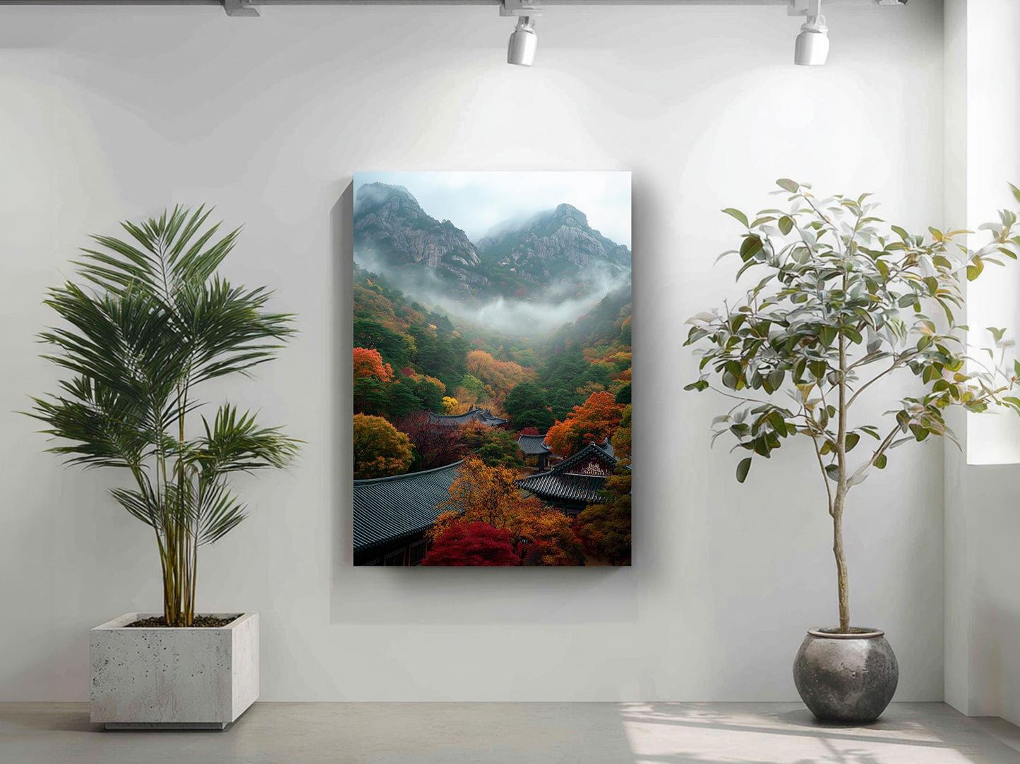 a serene indoor setting with a large painting of a mountainous landscape hanging on the wall, flanked by two potted plants.