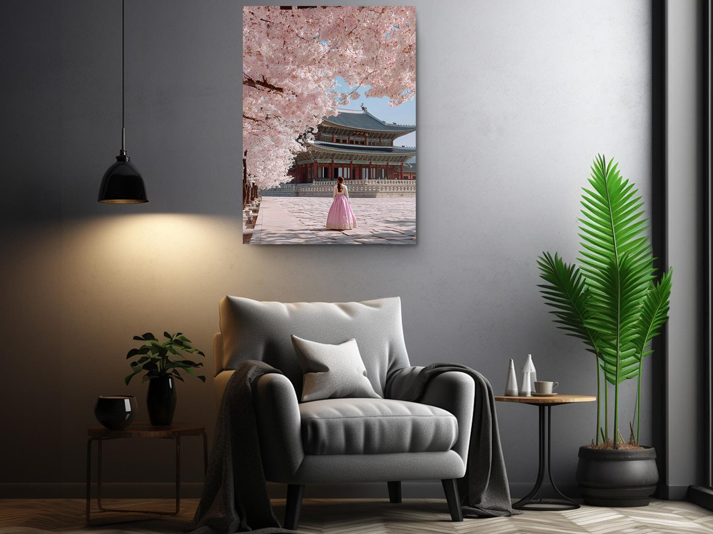 a living room with a gray armchair, a potted plant, and a framed picture of a woman in a pink dress standing in front of a traditional Japanese temple.