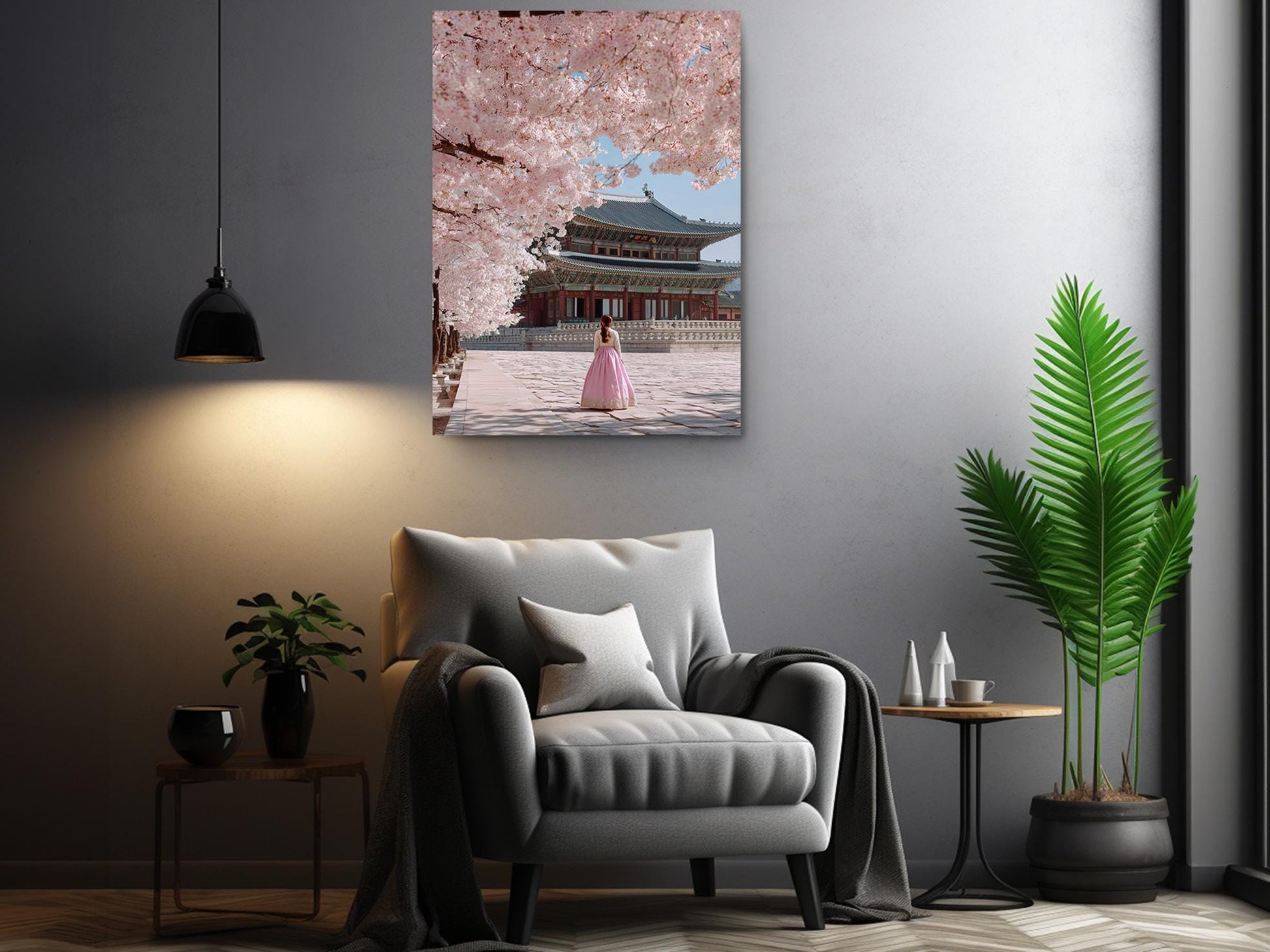 a living room with a gray armchair, a potted plant, and a framed picture of a woman in a pink dress standing in front of a traditional Japanese temple.
