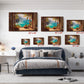 The image is a bedroom with a large bed, a desk, and a chair. Above the bed, there are five framed paintings of tropical landscapes, each with a different size and frame. The paintings are arranged in a row on the wall, creating a visually appealing display.