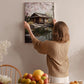 A woman hangs a framed picture of a serene Japanese garden on a wall in a cozy room.