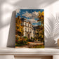 a painting of a large, ornate building surrounded by trees with autumn foliage, displayed on a white shelf against a white wall.