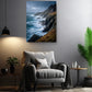 a living room with a gray armchair, a potted plant, and a framed photograph of a cliff overlooking the ocean.