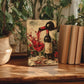 a painting of a wine glass with red wine being poured, surrounded by potted plants and books on a wooden surface.