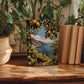 a wooden table with a framed painting of a scenic coastal landscape, surrounded by potted plants and books.